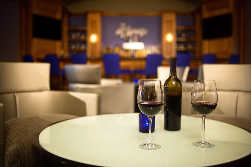 Two glasses of red wine on a lounge table at La Fontana Lounge inside Hilton Santa Clara, with bar seating in the background