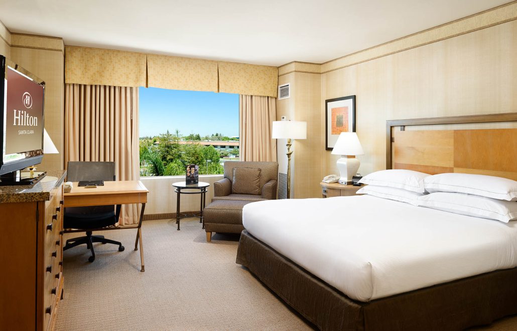 King bed guest room with desk and lounge chair at Hilton Santa Clara, part of Santa Clara hotel room tours.