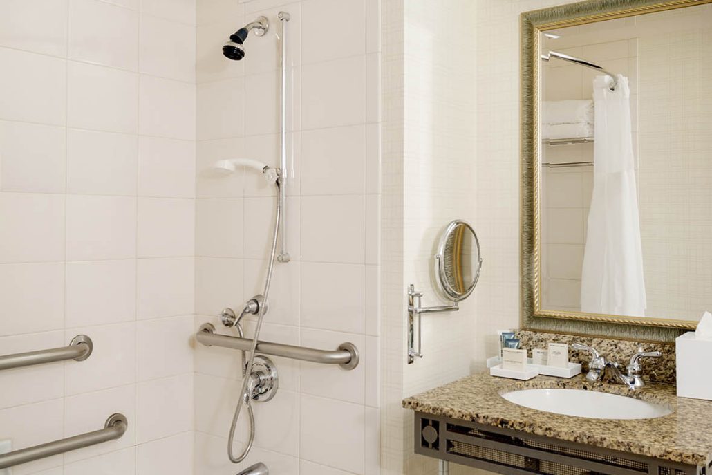 Accessible bathroom at Hilton Santa Clara with grab bars, handheld shower, and ADA-compliant bathtub setup.