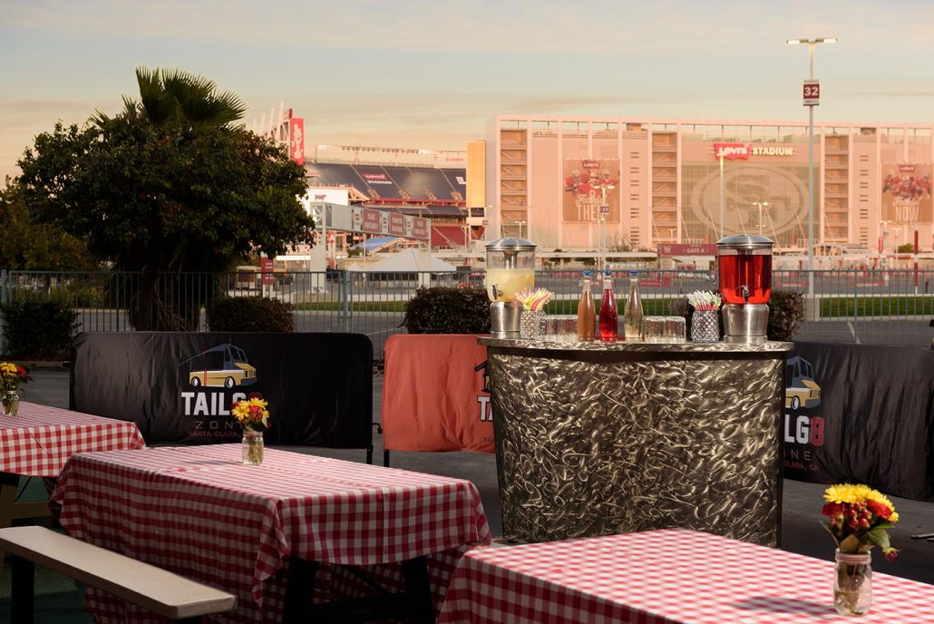 Tailgate Zone setup with a bar and picnic seating overlooking Levi’s Stadium at sunset.