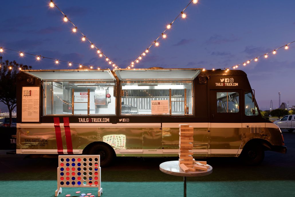 Food truck at Hilton Santa Clara Tailgate Zone with string lights overhead and a colorful chair in the foreground.