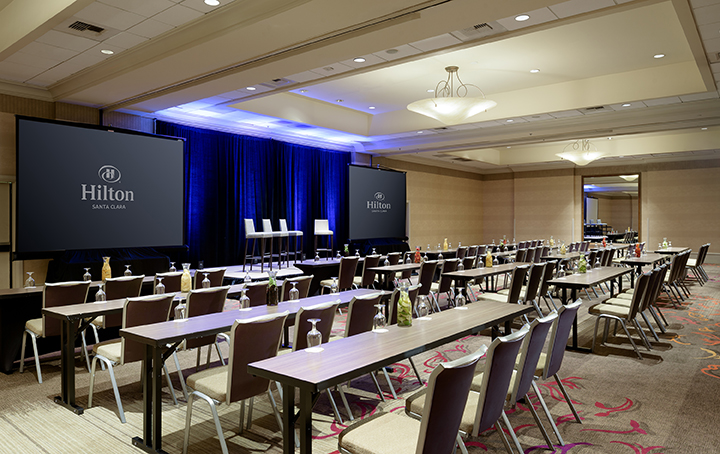 Sierra Ballroom at Hilton Santa Clara set up in school room style with tables, chairs, and presentation screens; accommodates up to 300 guests