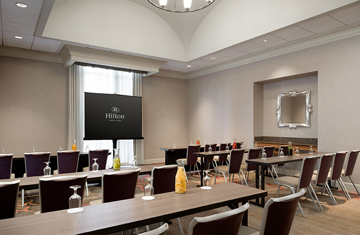 Yosemite Meeting Room at Hilton Santa Clara set up in school room style with tables, chairs, and presentation screen; accommodates up to 50 guests